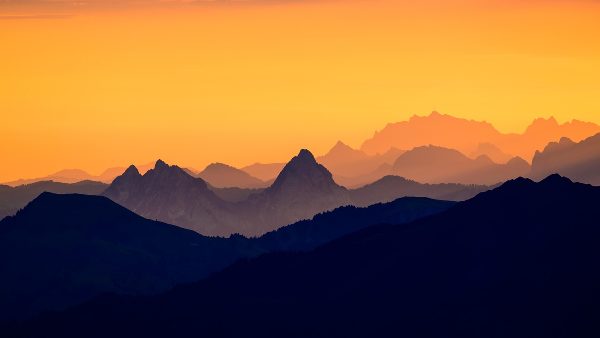 Mountain ridges at sunrise under an orange sky