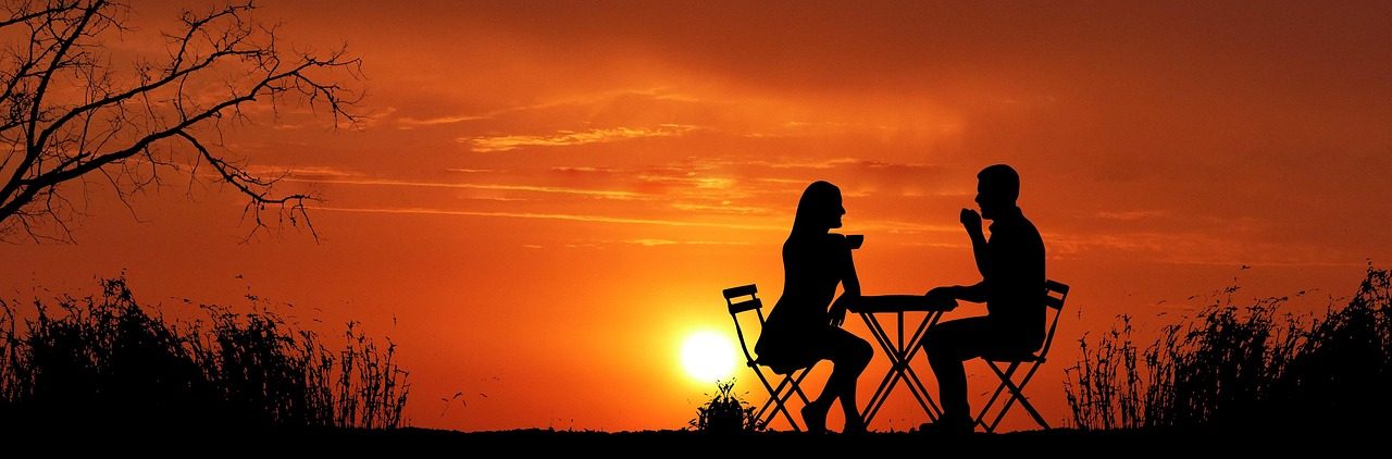 A couple at a dinner table at sunset